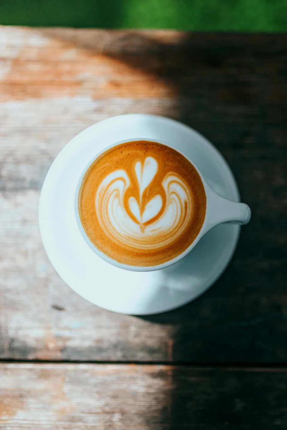 A cup of coffee on a wooden table photographed by Nathan Dumlao.